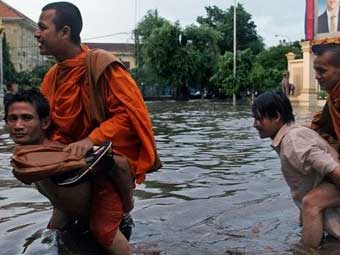 Жители Пномпеня переносят монахов после сильного дождя. Фото AFP